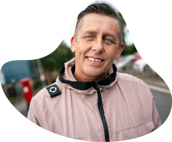 A photo of a man smiling, wearing a raincoat in the street