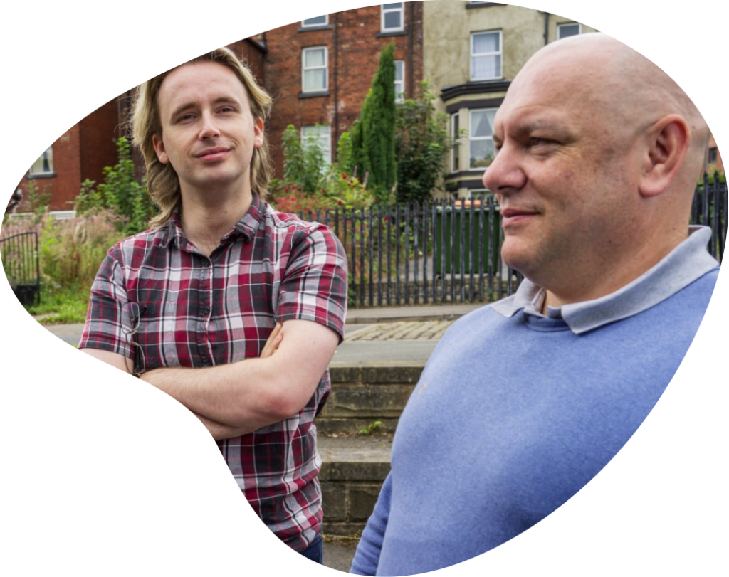 Two men standing together in front of housing
