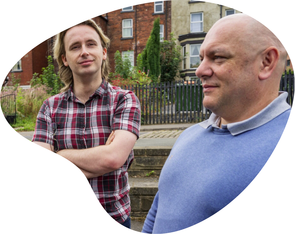 Two men standing together in front of housing