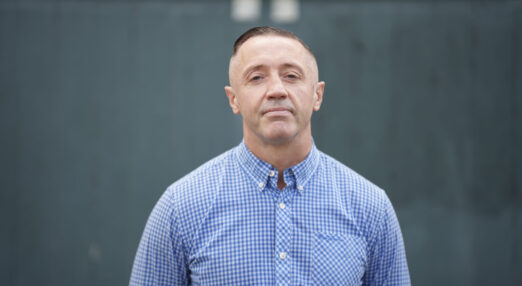 A photograph of Steve, a volunteer at Waythrough's Reconnect service. He is looking straight at the camera and wearing a blue and white checked shirt.